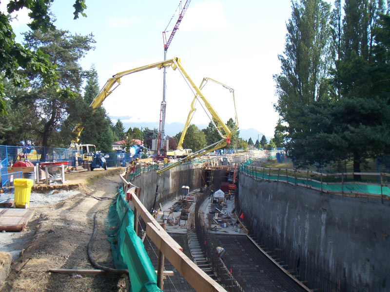 Boom pump reaching across a shored excavation for a foundation wall pour