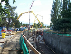 Boom pump reaching across a shored excavation for a foundation wall pour