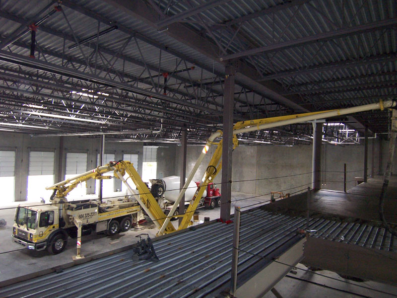 Boom pump working inside a steel-framed warehouse to place an interior slab