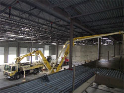 Boom pump working inside a steel-framed warehouse to place an interior slab