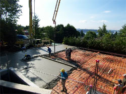 Finishing crew working a large rebar-reinforced slab on a hillside lot